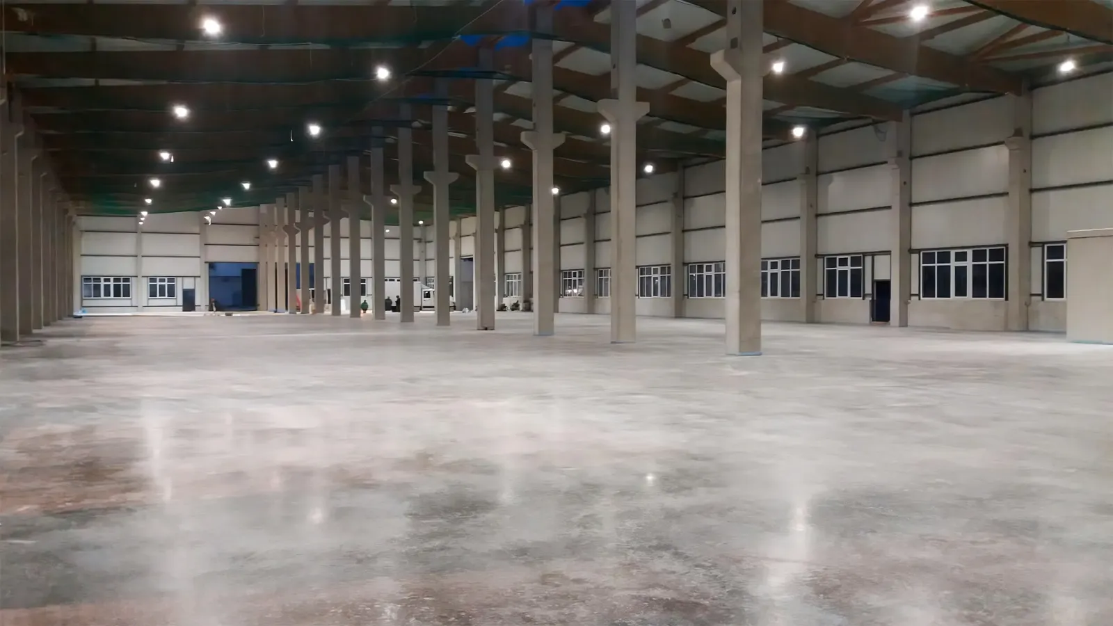 Große leere Industriehalle mit poliertem Betonboden und hohen Betonsäulen